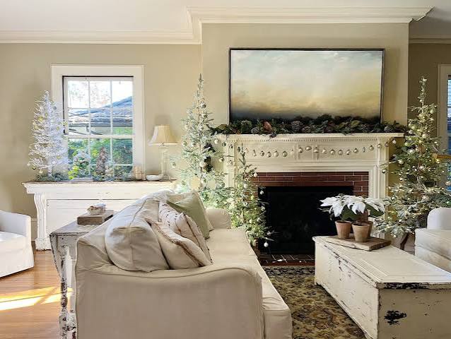 Cozy Living Room with Multiple Flocked Trees and Garlanded Fireplace Cozy Living Room with Multiple Flocked Trees and Garlanded Fireplace — White Christmas Decor