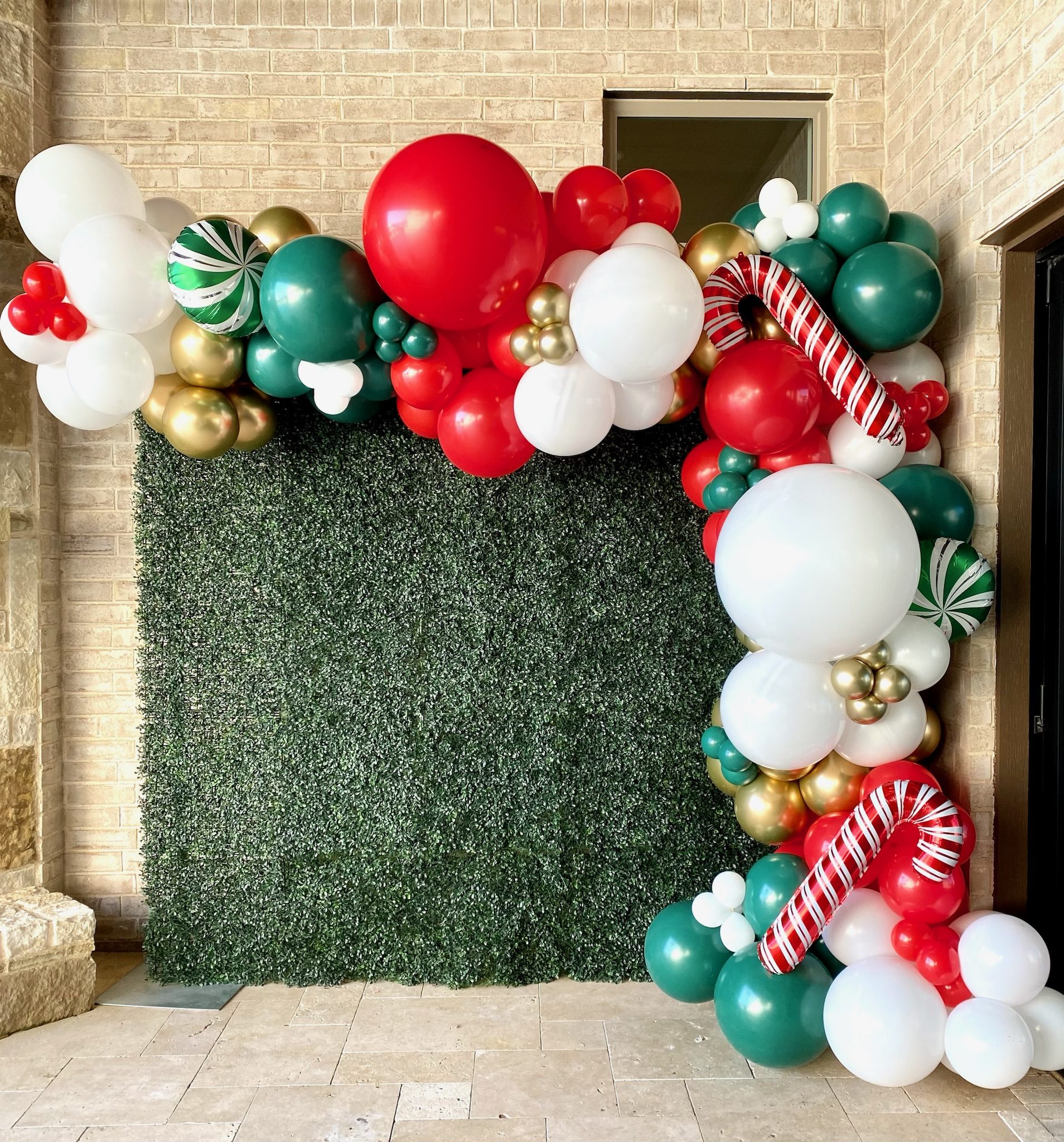 Festive Red, Green, Gold, and White Balloon Garland Across a Boxwood Hedge Festive Red, Green, Gold, and White Balloon Garland Across a Boxwood Hedge — Christmas Balloon Garland