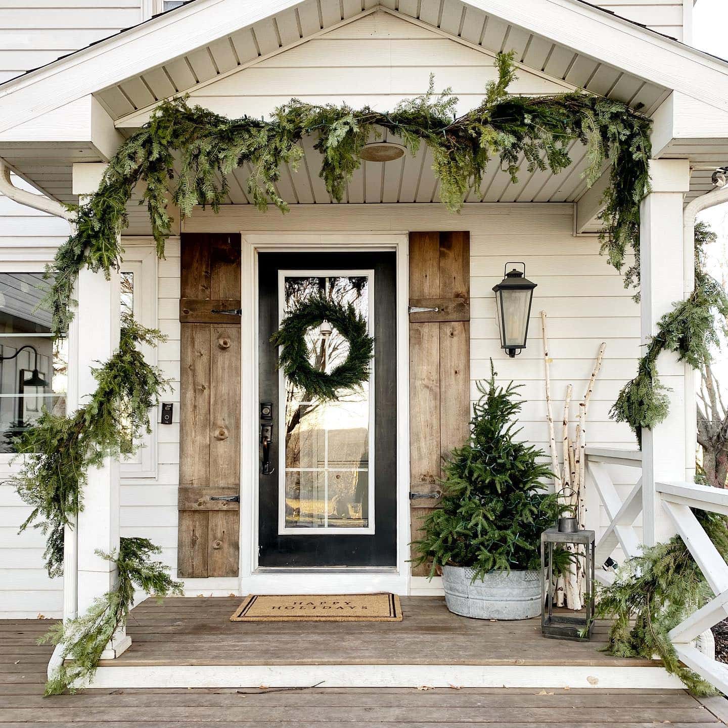 Dark Wood Door with Abundant Evergreen Garland and Shutters — Farmhouse Christmas Porch