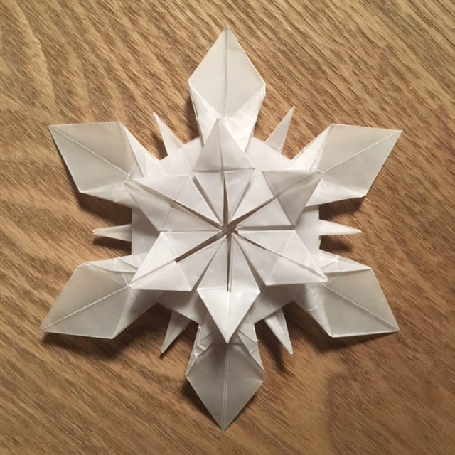 Detailed White Origami Snowflake on Wood Surface — Paper Snowflakes