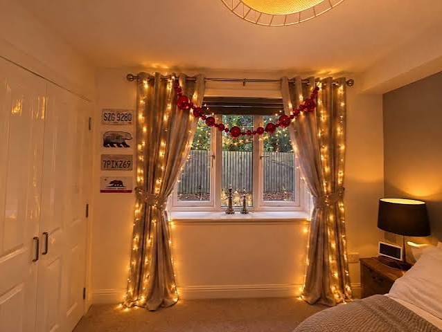 Festive Christmas Garland and Fairy Lights Framing a Bedroom Window — Christmas Fairy Lights Window