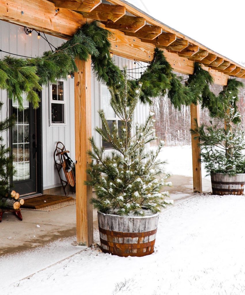 Rustic Porch with Snow-Dusted Trees in Barrels — Christmas House Exterior Decor