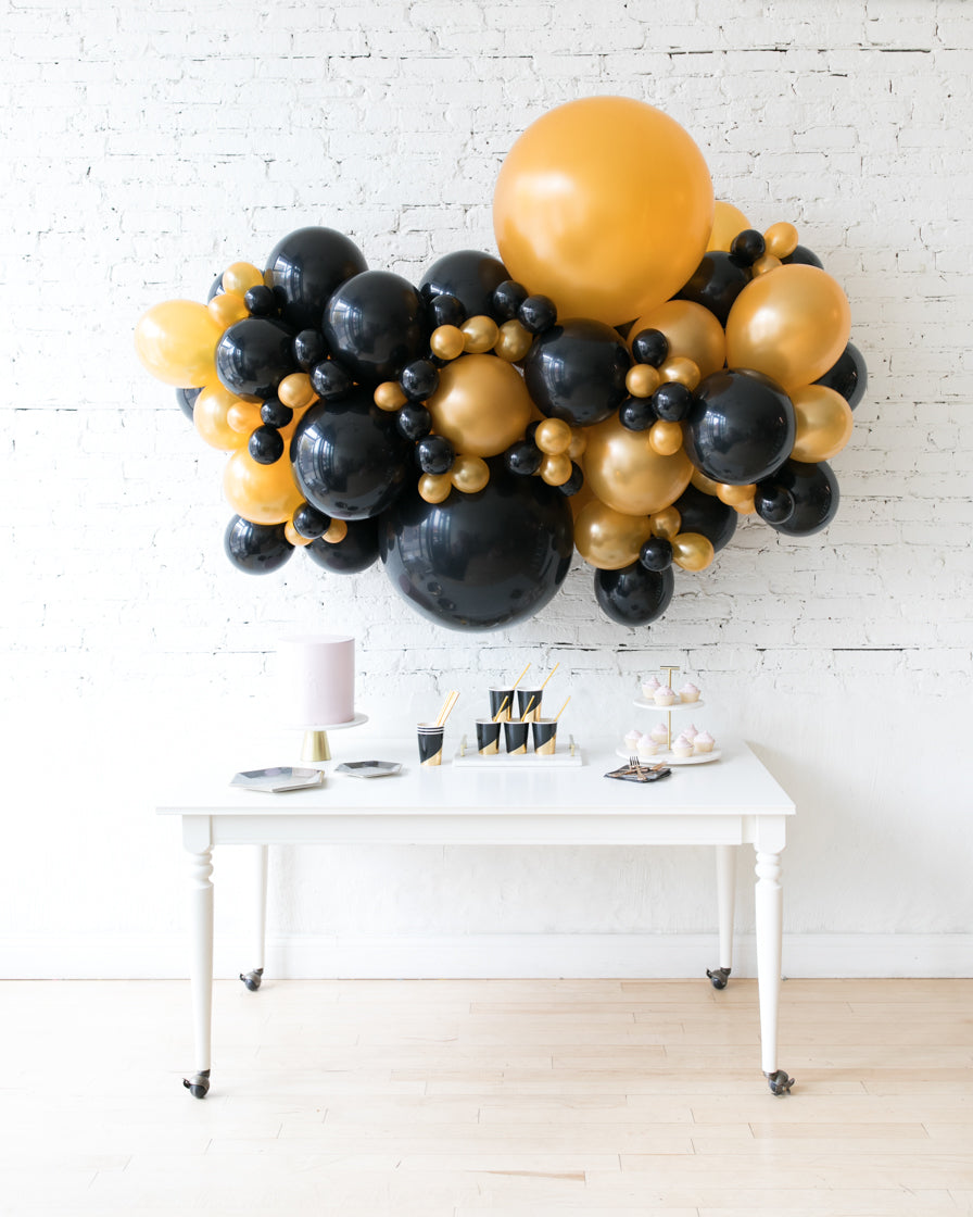 Modern Black and Gold Balloon Garland on Brick Wall — New Years Eve Backdrop