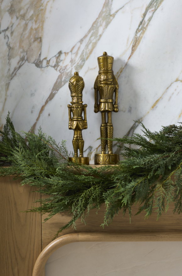 Ornate Brass Nutcrackers Flanked by Evergreen Garland on Mantel Ornate Brass Nutcrackers Flanked by Evergreen Garland on Mantel — Vintage Christmas Decor